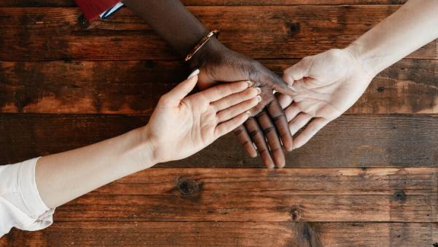 Three hands joined showing support for each other