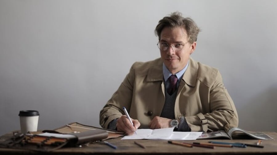 Serious male manager writing in papers while working at table