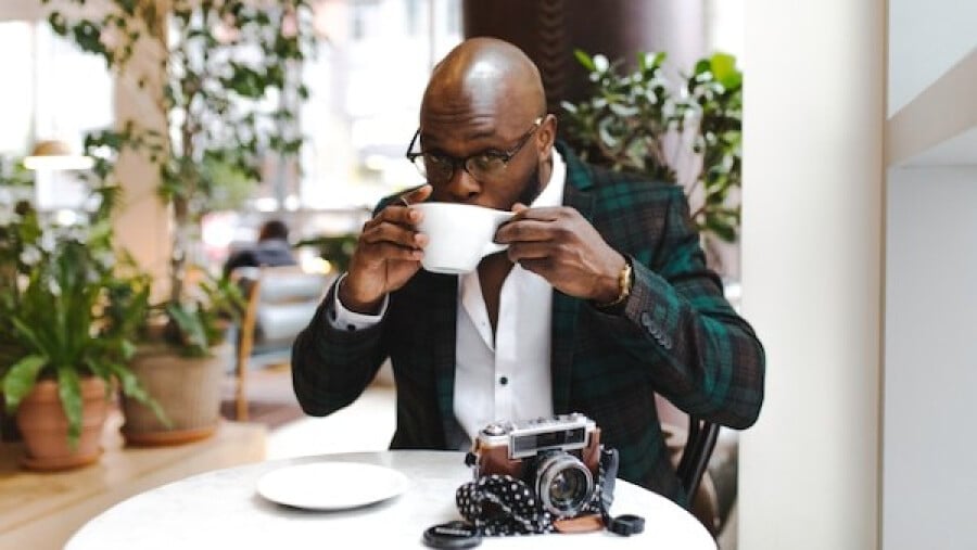 Man Sitting in Front of Round Table While Sipping from White Ceramic Mug