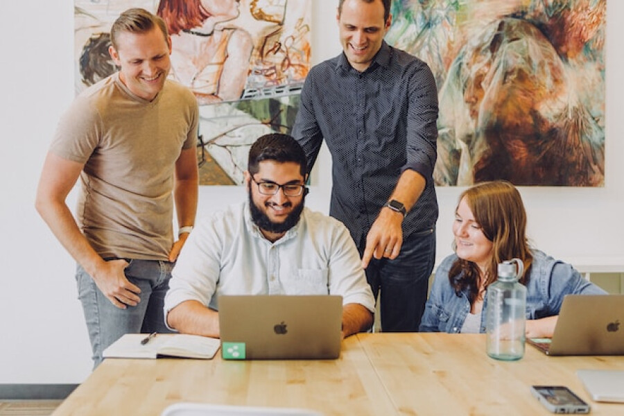 Team review in startup office with macbook and artwork. Team working together in progressive workplace