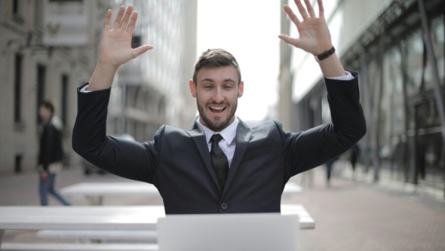 Man in black suit raising his hands in the air