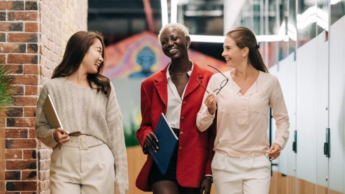 Diverse businesswomen smiling and walking together in a modern workplace