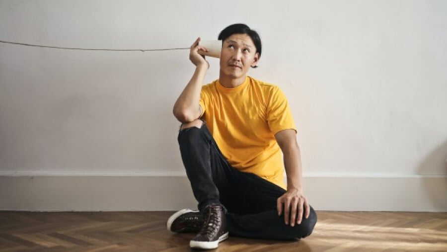 A man listening to a paper cup phone
