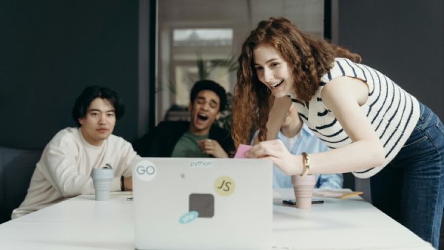People laughing while looking at a laptop screen