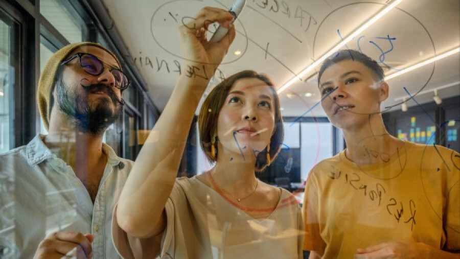 Coworkers writing notes on glass window