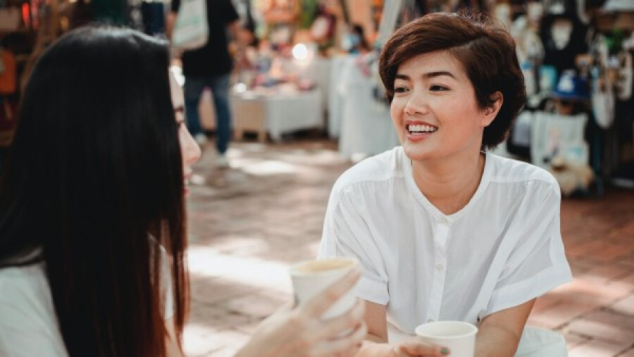 Two women drinking coffee and chatting in an outdoor cafe