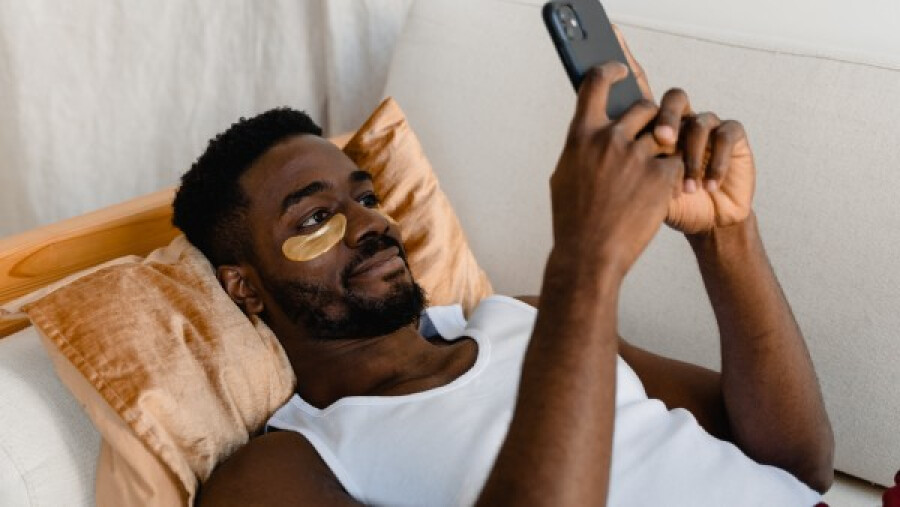 Man with under-eye patches using a phone