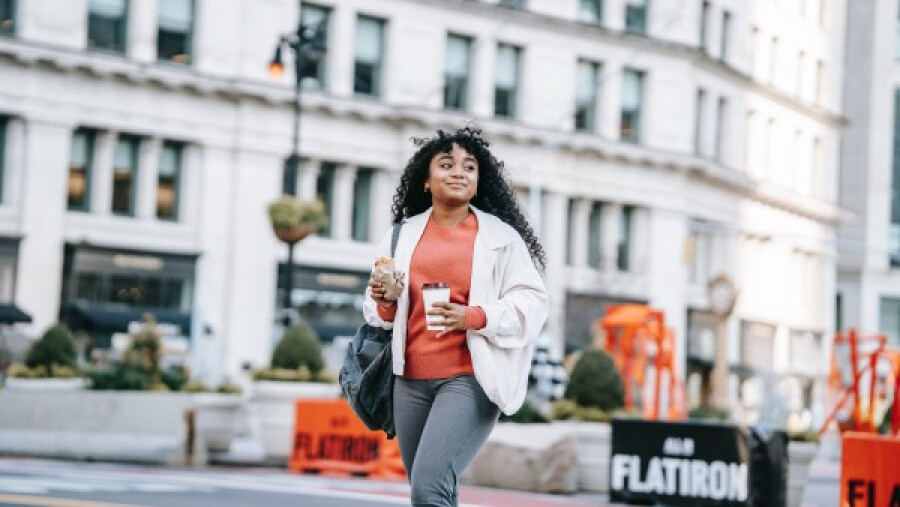 Woman with takeaway coffee and sandwich on street