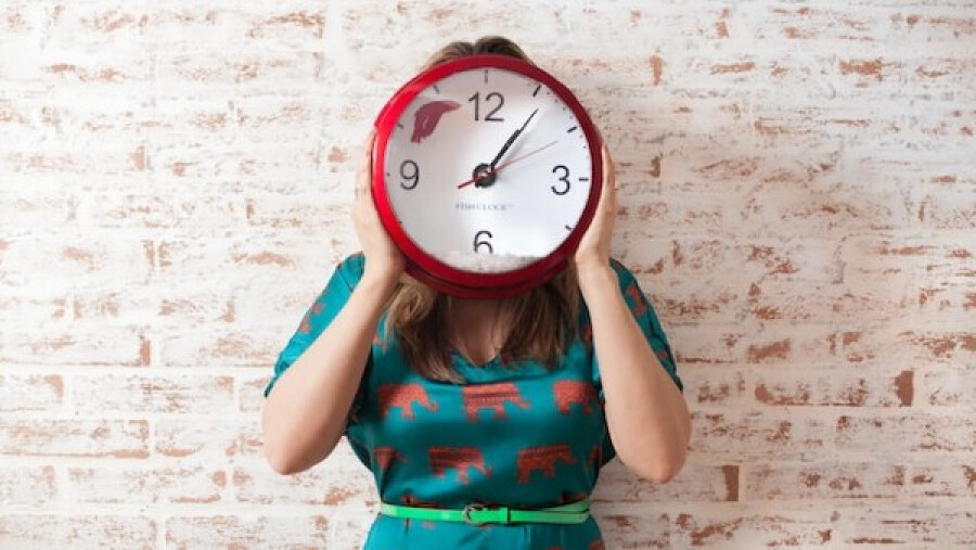 woman covering face using wall clock