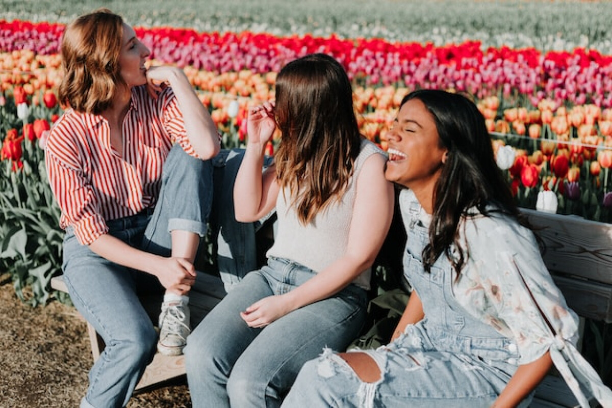 Three women sitting and laughing in a field
